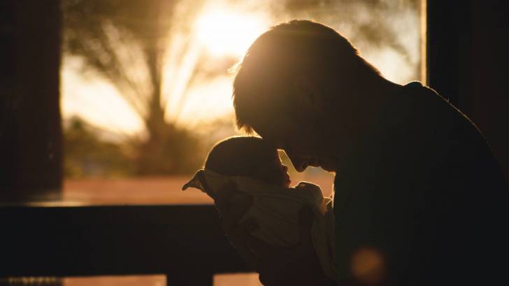 father holding young baby looking at him