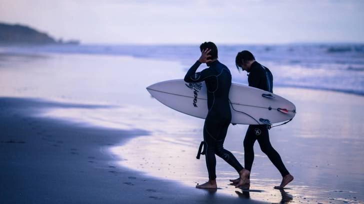 men going surfing at dusk