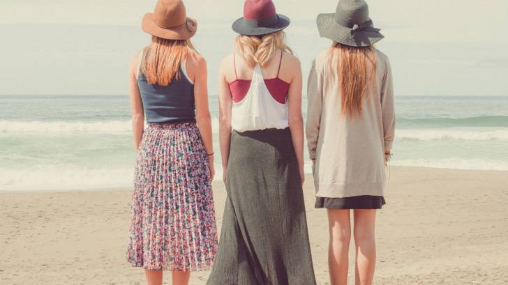 three young women string at the ocean