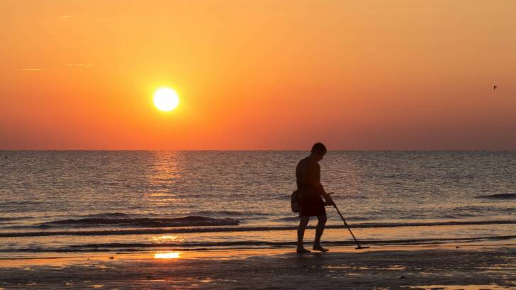 man on beach hunting for treasure