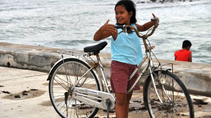 young filipino girl on a bike near the beach