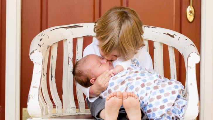 older sibling kissing new born baby