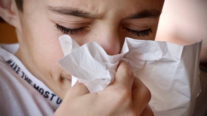 boy sneezing into a hankie