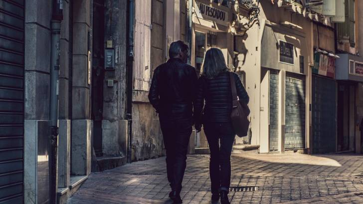 older couple walking thru an old town in europe