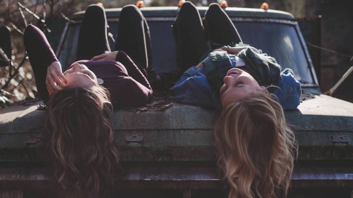 young girls lying on a car chatting