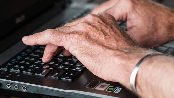 older hands with arthritis typing on a keyboard