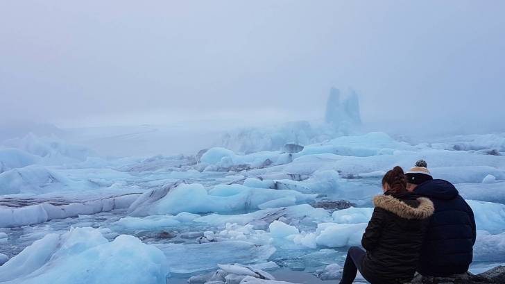 couple sitting on the edge of an iceberg