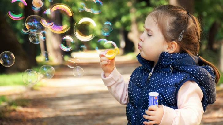 young girl blowing bubbles