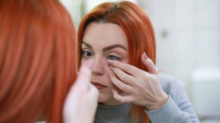 woman putting contact lens in her eyes