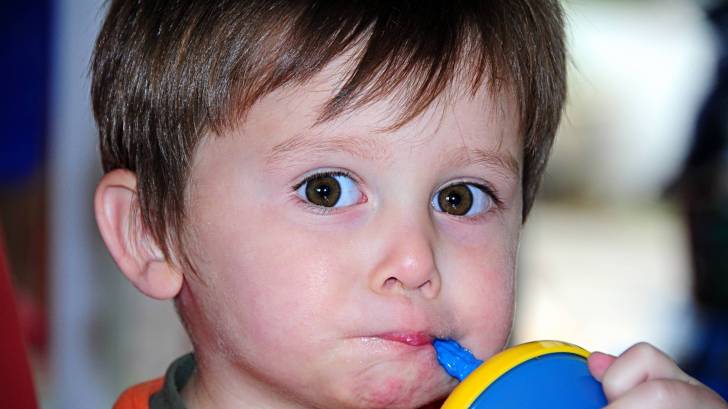 young boy drinking from a sippy cup