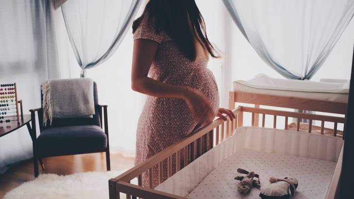 pregnant mom looking at her babies crib