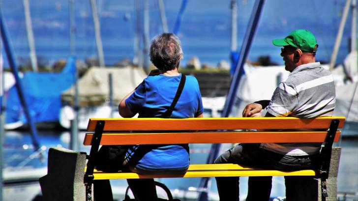 older couple sitting on a bench at a dock