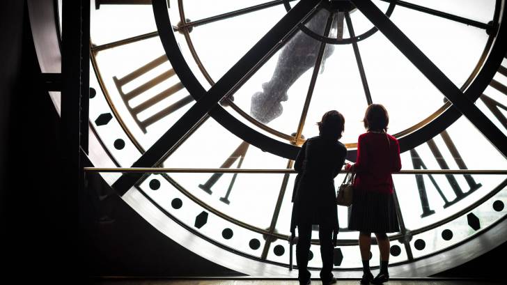 women in front of a big clock