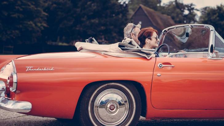 old red T bird with couple driving