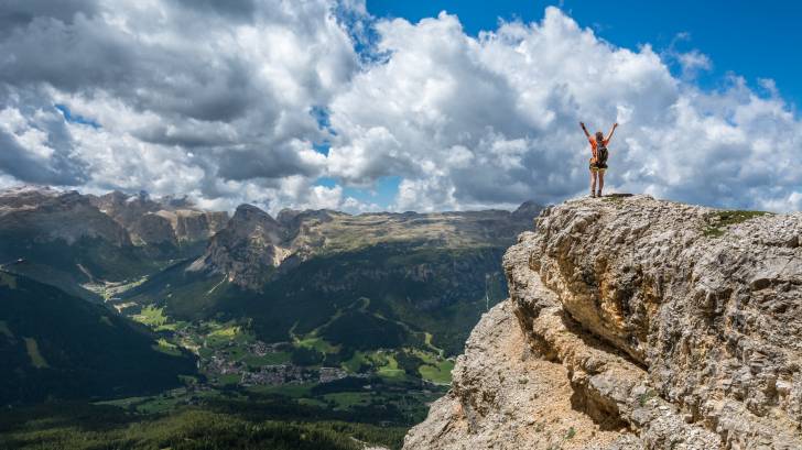 mountain with a person celebrating on the top of it