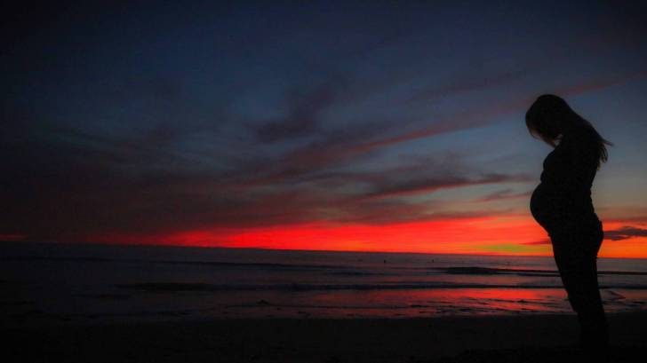 pregnant woman on beach at sun set