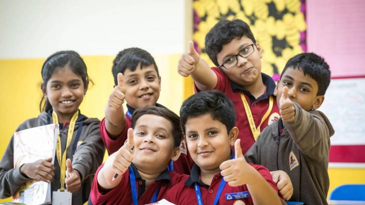 school children smailing and thumbs up