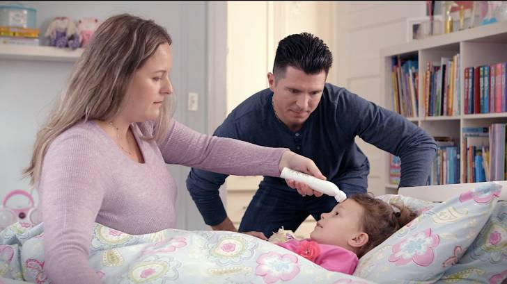 Mom taking temperature of little girl