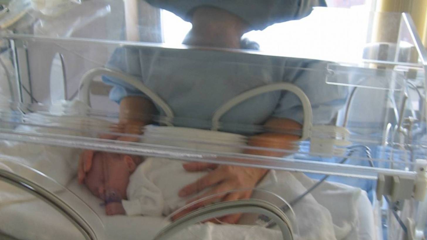 preterm baby in an incuboator mom holding inside