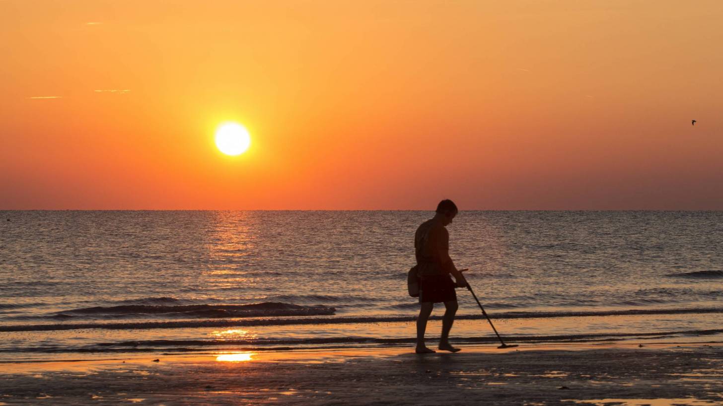 man on beach hunting for treasure