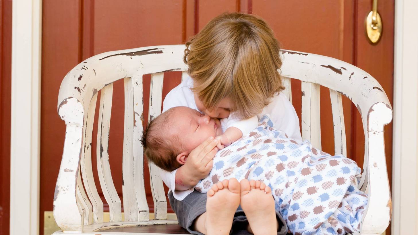 older sibling kissing new born baby