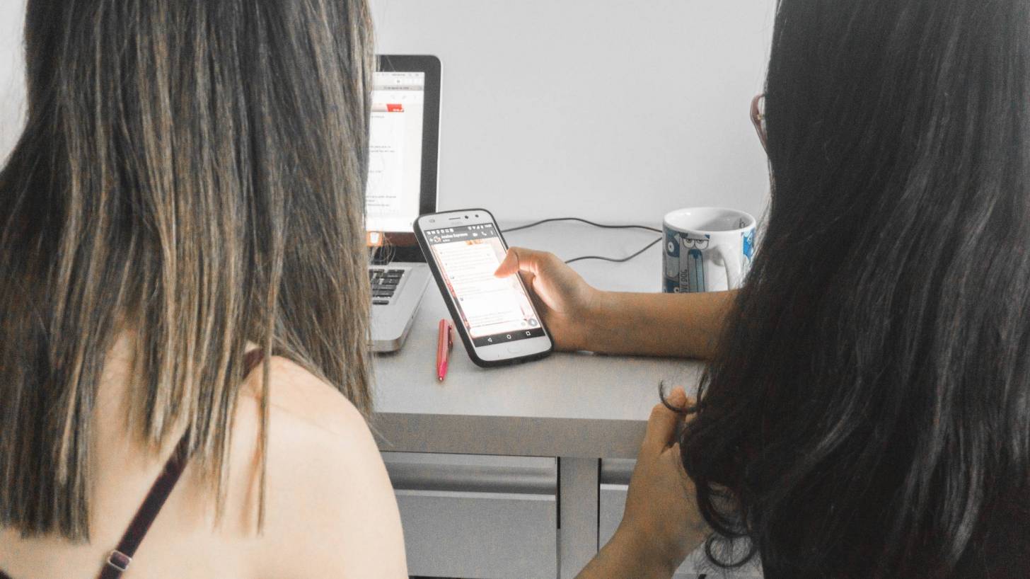 two women discussing information on their cell phone