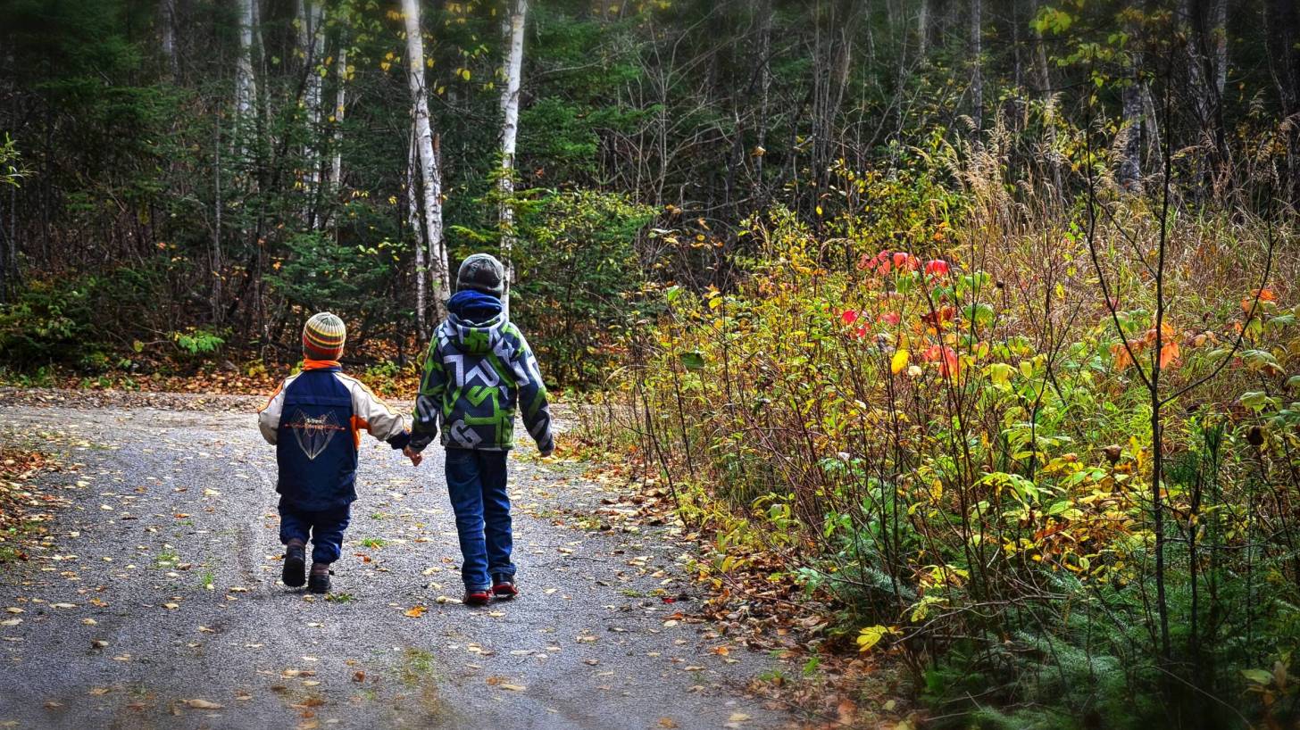 two young children walking along a road holding hands