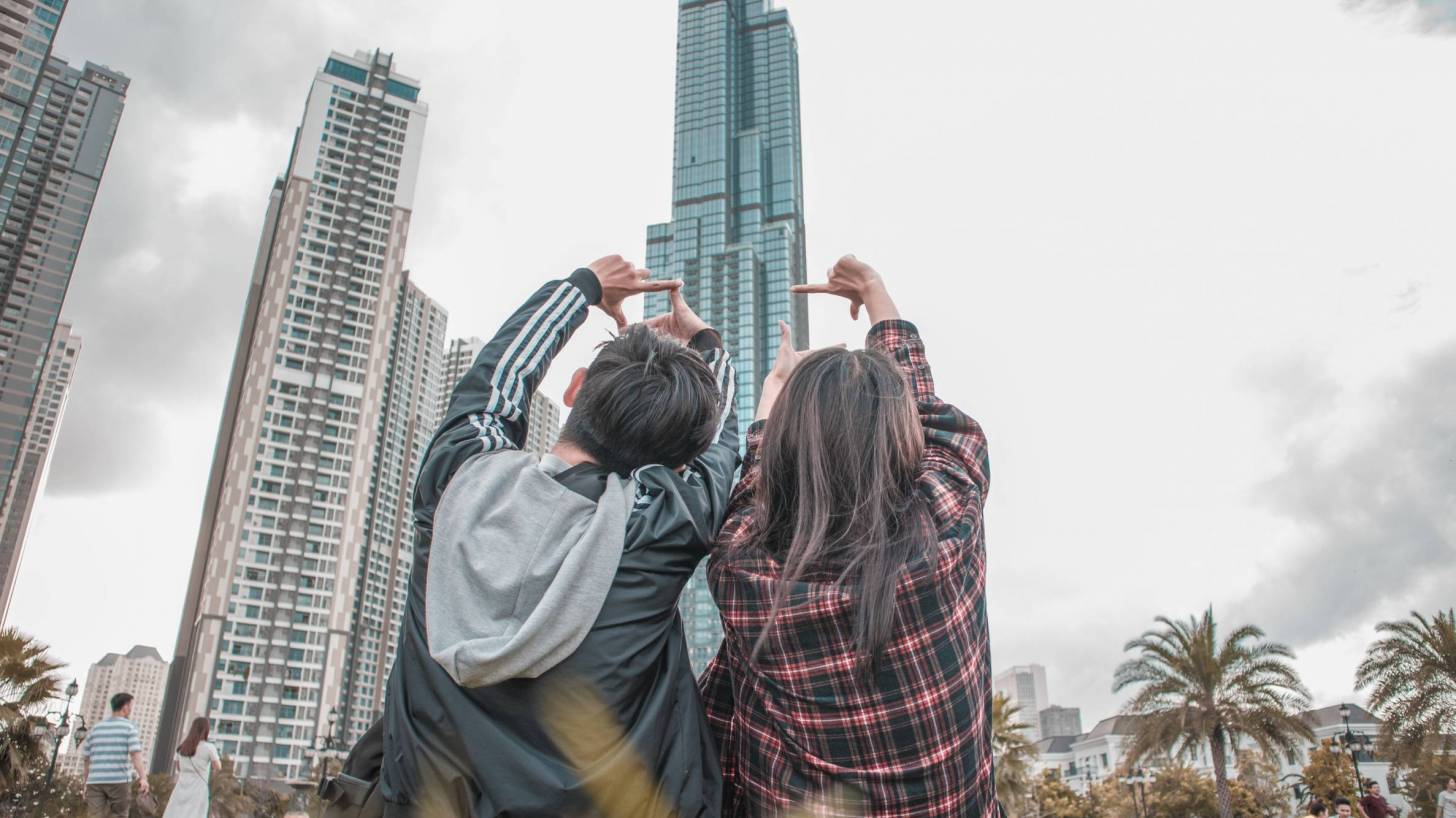 young couple sitting n the lawn looking at large buildings