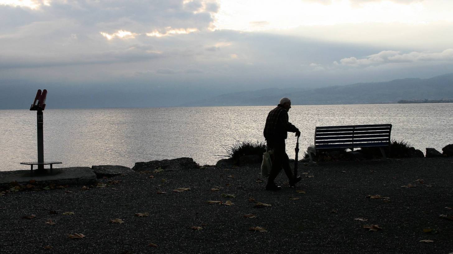 dawn is rising, man walking with a cane near the sound