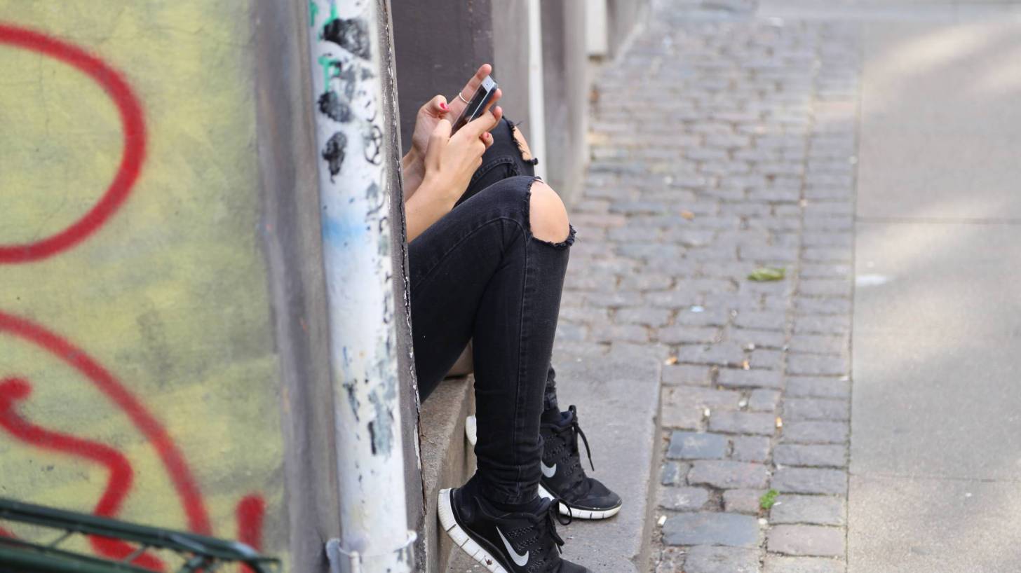 girl sitting on a stoop looking at cell phone