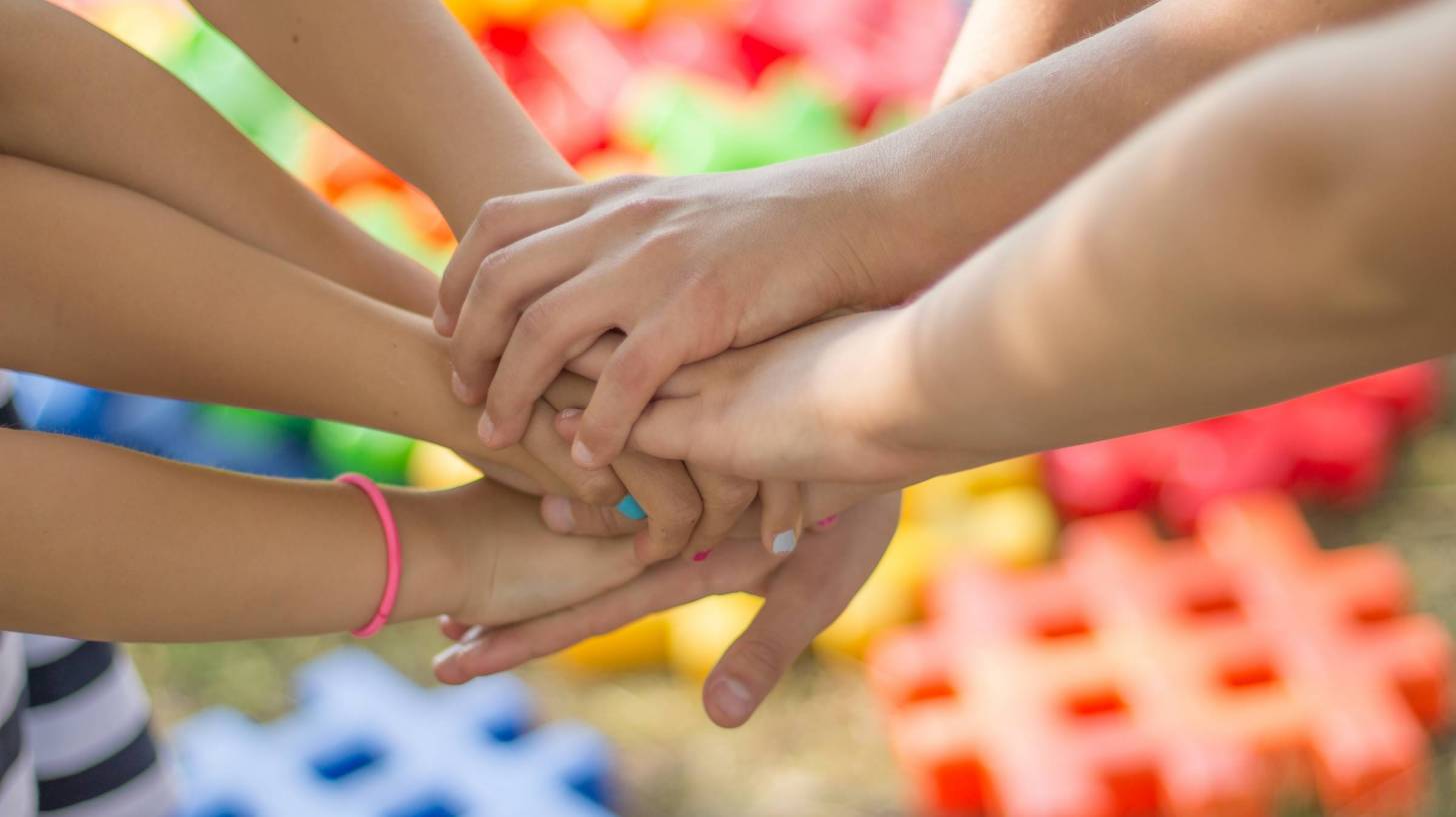 childrens hands on top of each other, playing a game