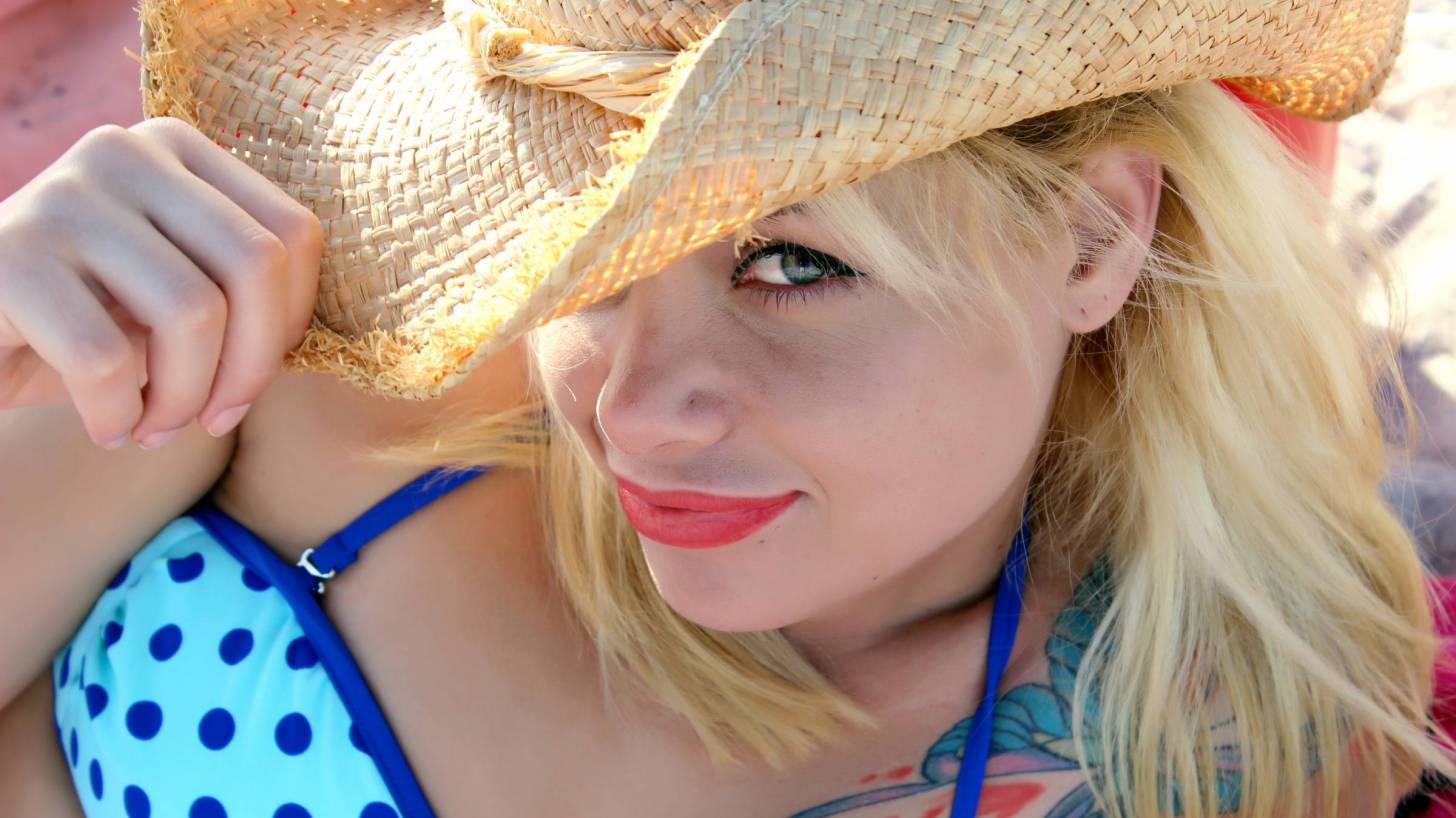 woman at beach with a hat on to block the sun from her face