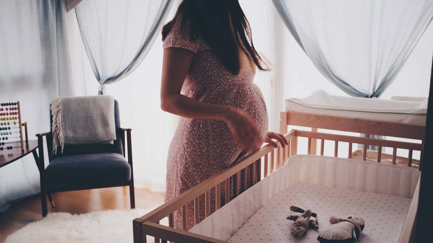 pregnant mom looking at crib