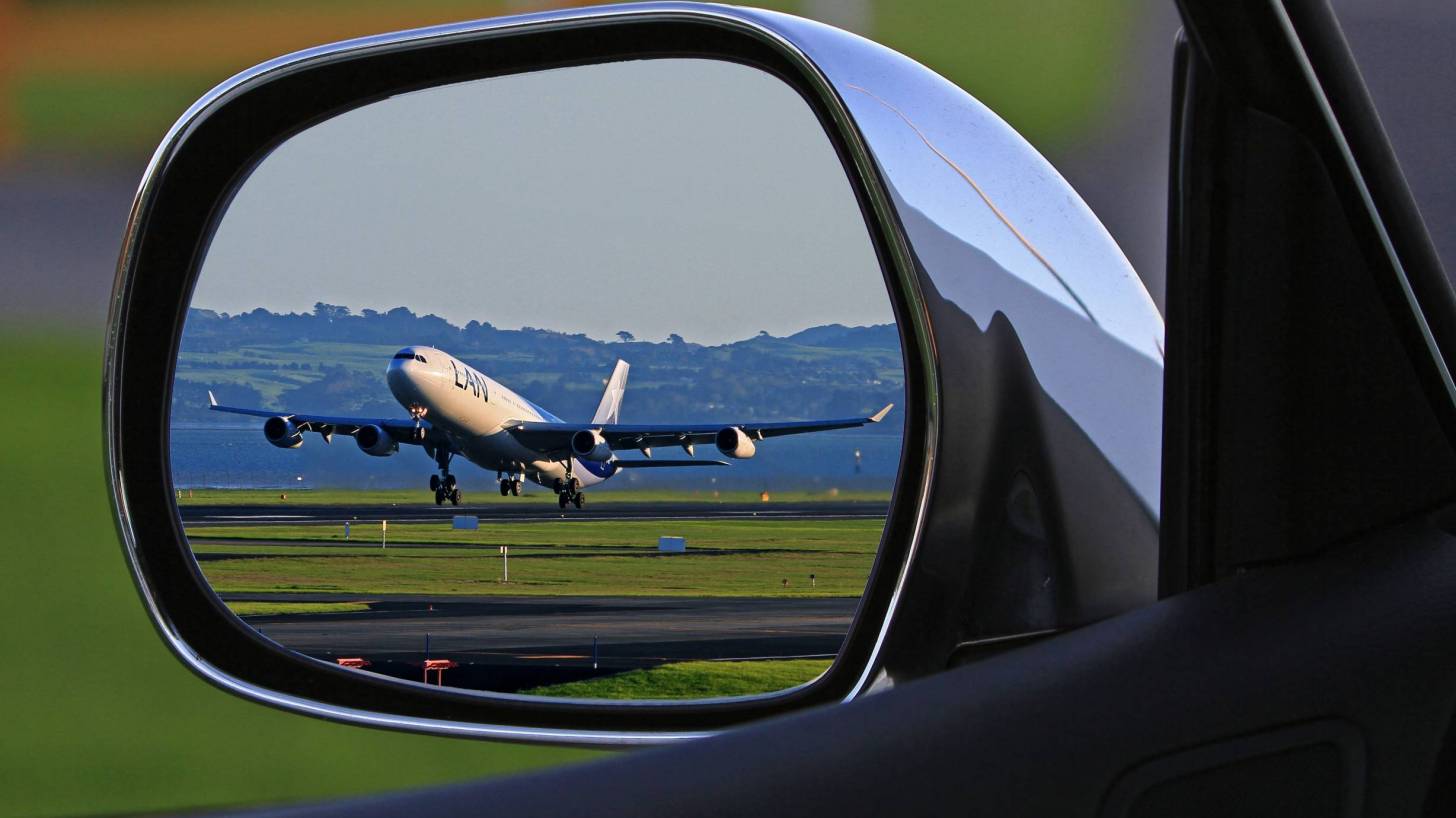 plane in a rear view mirror of a car taking off