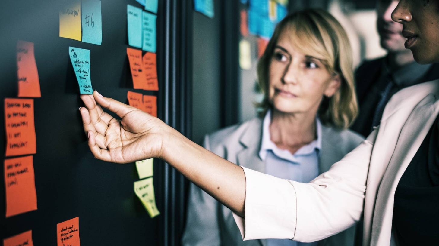 people looking at a meeting board to determine next steps