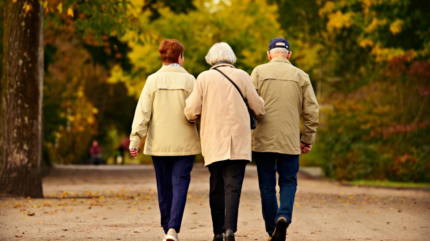 three older friends walking arm in arm