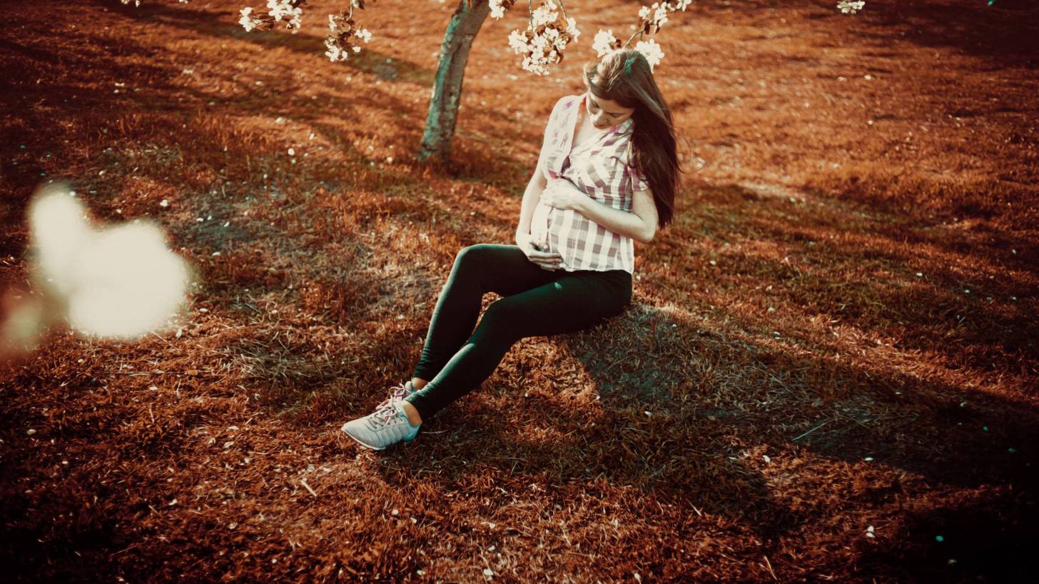 pregnant women sitting in the fall sunlight