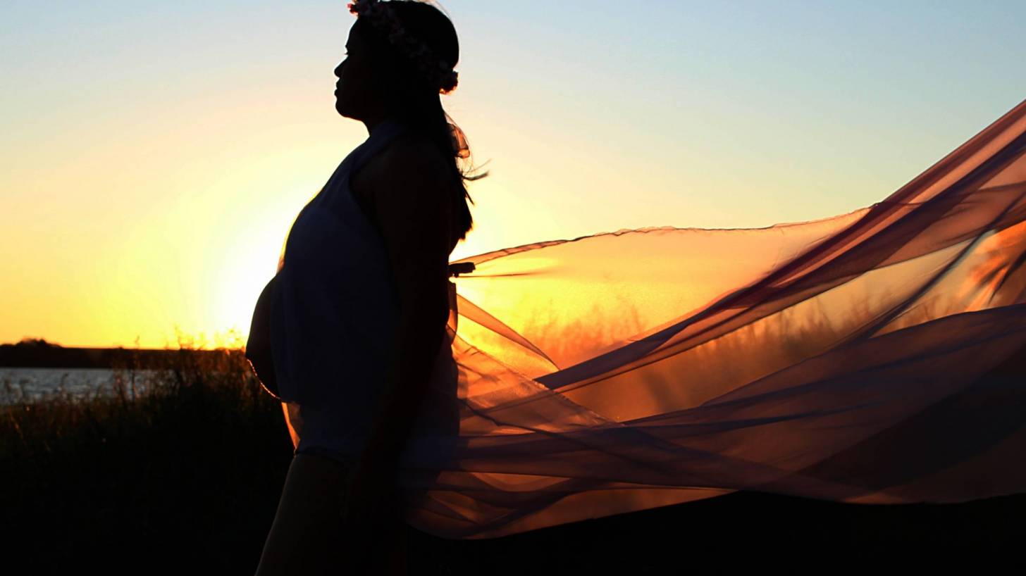 pregnant lady at the beach sun setting wind blowing