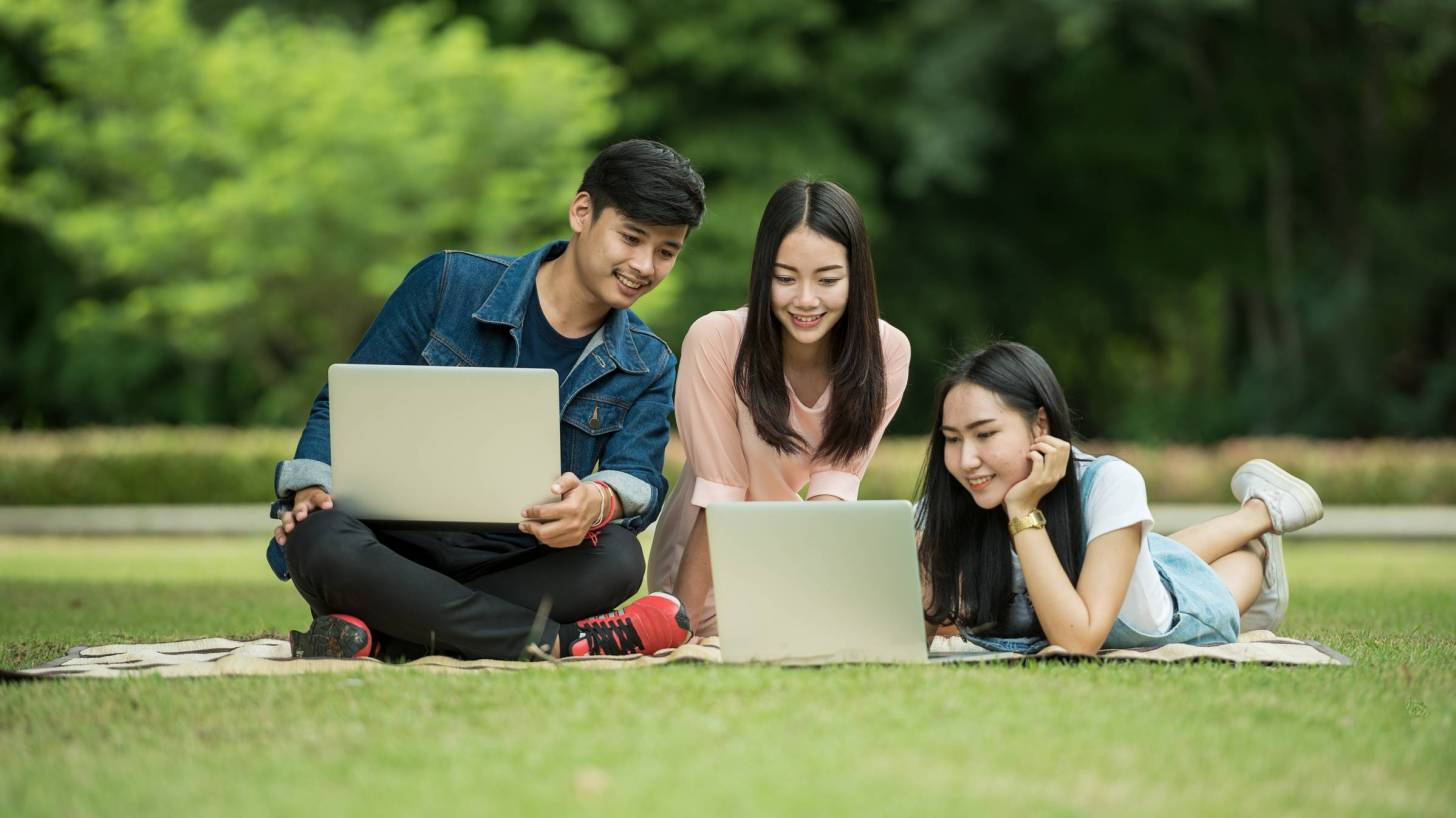 young adults studying on lawn