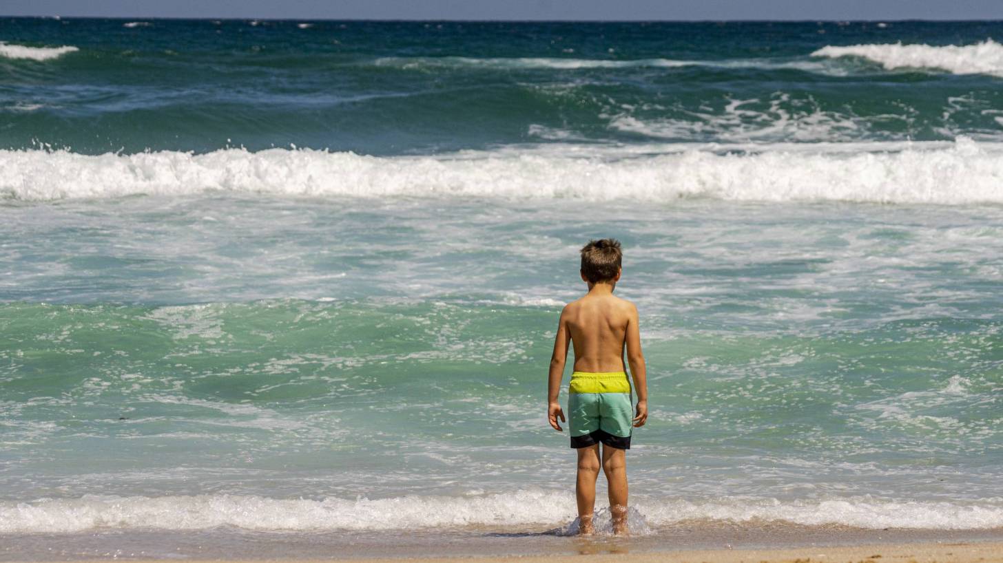 young boy looking at the ocean surf