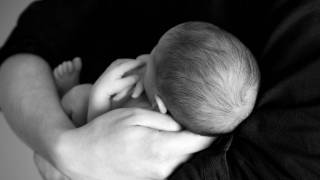 young new born in arms protecting the baby