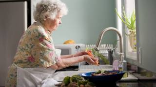 older woman in kitchen washing veggies