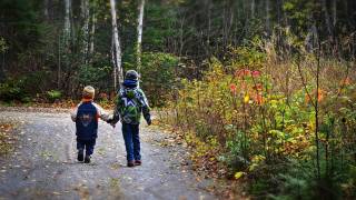 two young children walking along a road holding hands