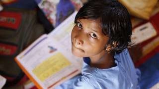 young indian girl studying, looking up at the camera