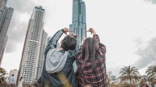 young couple sitting n the lawn looking at large buildings