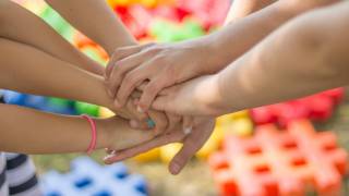 childrens hands on top of each other, playing a game