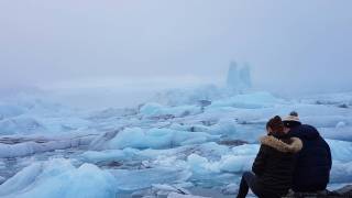 couple sitting on the edge of an iceberg