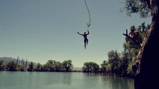 man swinging from a rope over a lake and letting go