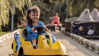 happy girl driving at a kiddie car park