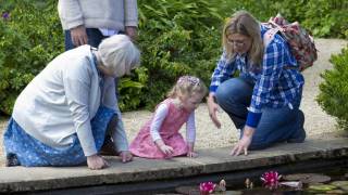 grandparents with grandaughter looking at a pond